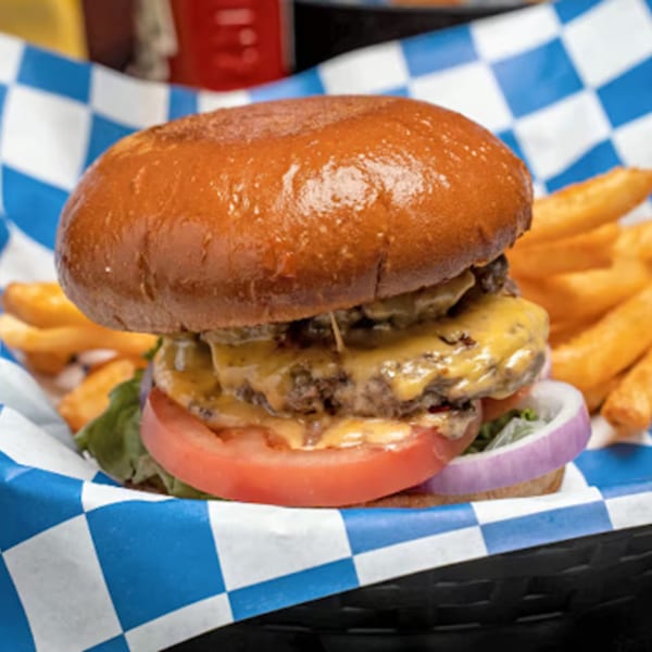 A Hot Pockets Sports Bar double cheeseburger with lettuce, tomato, and onion, served with fries.