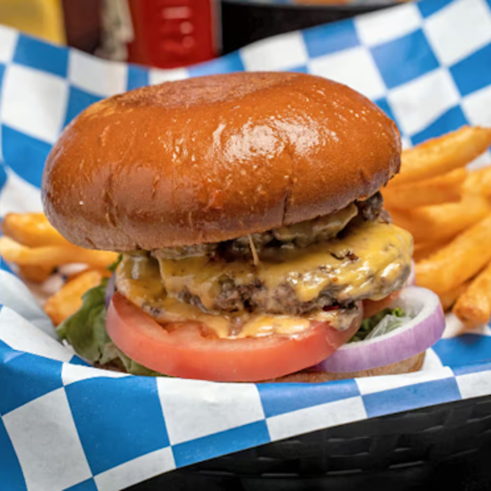 A Hot Pockets Sports Bar double cheeseburger with lettuce, tomato, and onion, served with fries.